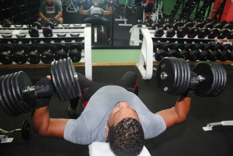 a man doing dumbs at the gym while lying on one side