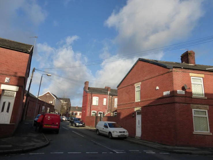 cars parked on the side of a road next to brick houses