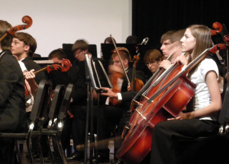 a conductor and orchestra with cellos and keyboards