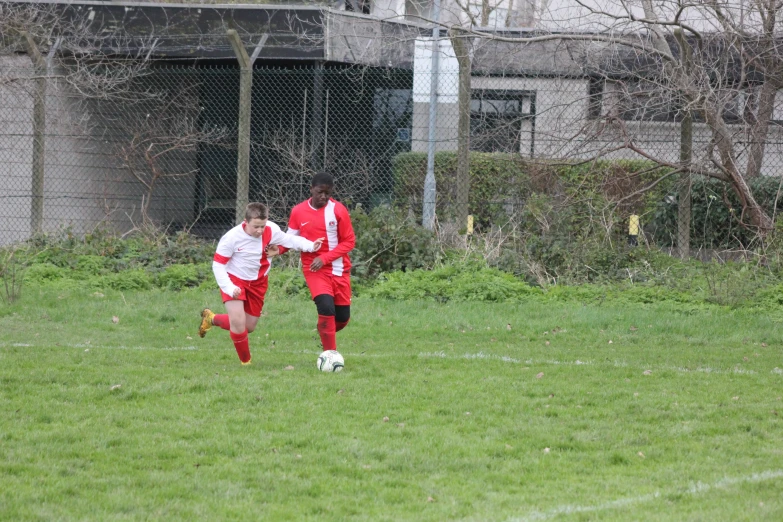 two players in uniform playing soccer in the grass