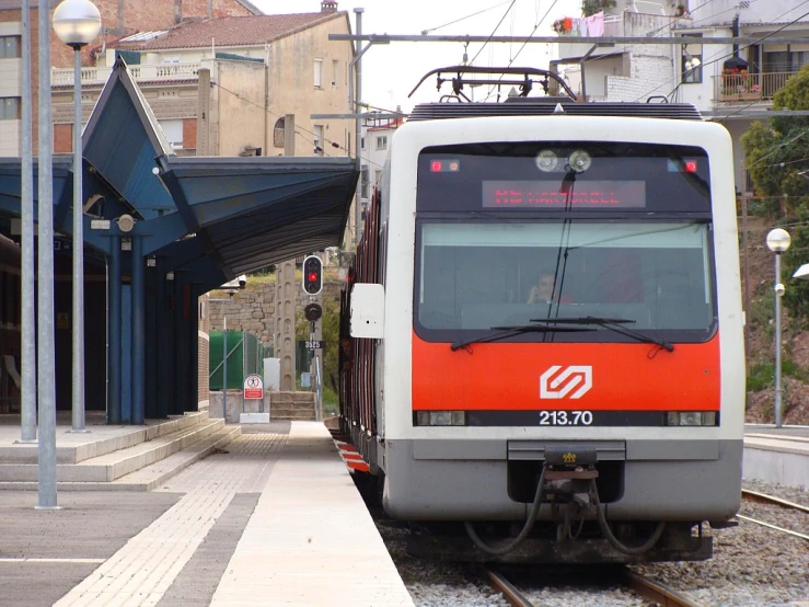 a silver and orange train traveling on the tracks