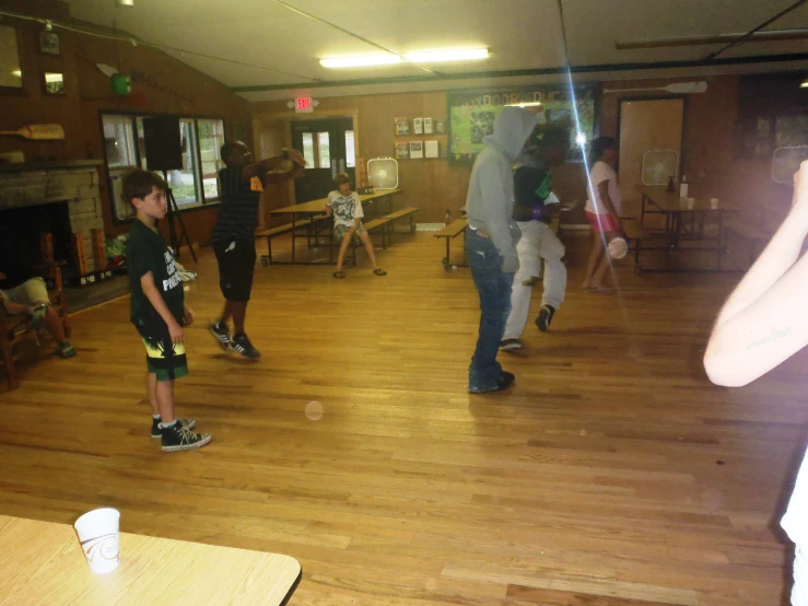 several people are dancing in a room with wooden floors