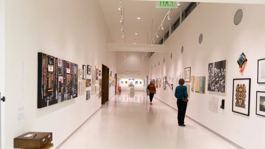 a woman and a boy walking down a hallway between two white walls