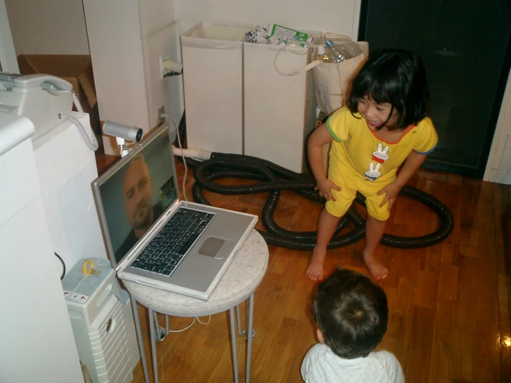 a  is sitting on the floor while playing with a laptop computer