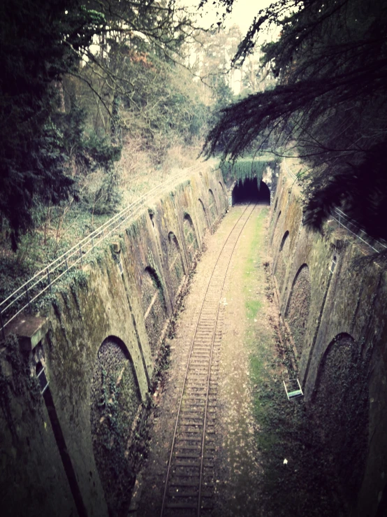 looking down the tracks in a tunnel leading to a small cabin