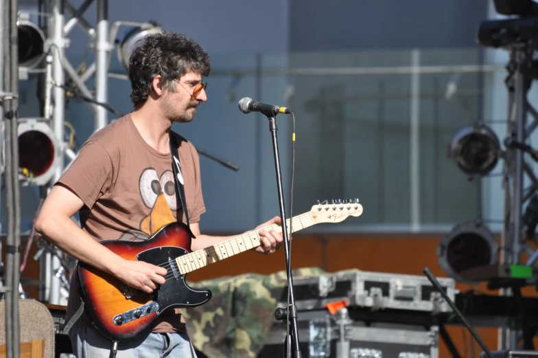 a person standing in front of a microphone while playing a guitar
