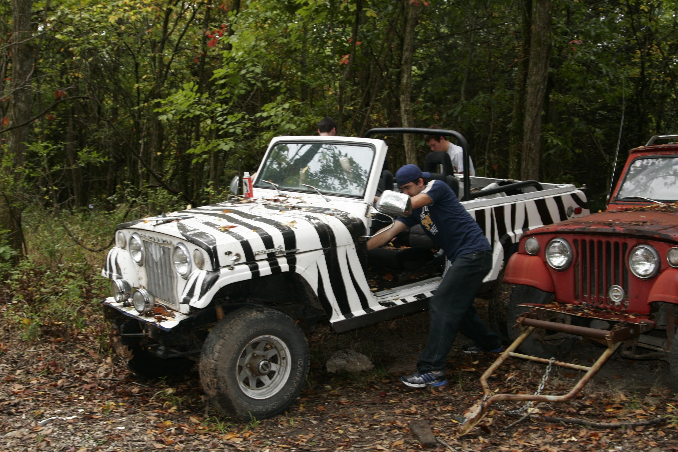 two men painting on a jeep on the forest