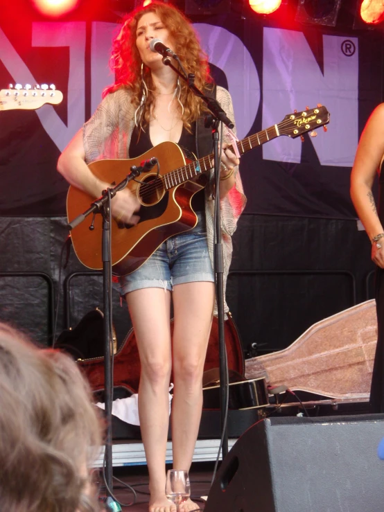 a woman standing in front of a microphone with her guitar