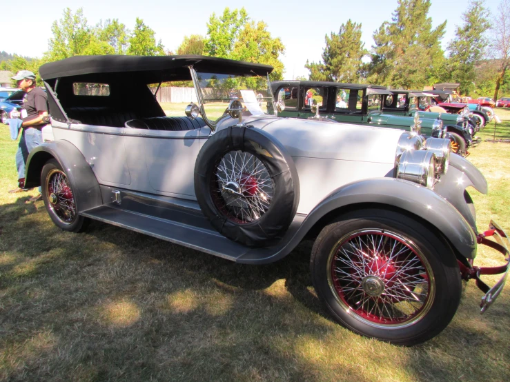 an antique model t car with several chrome rims is parked outside
