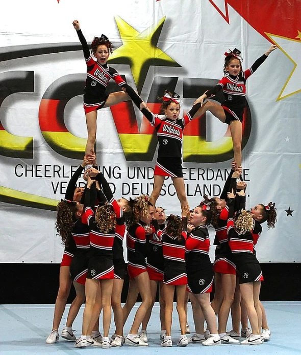 cheerleaders performing in a competition with one doing a hand flip