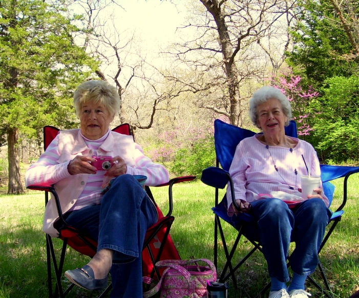 two old ladies sitting in chairs talking and eating