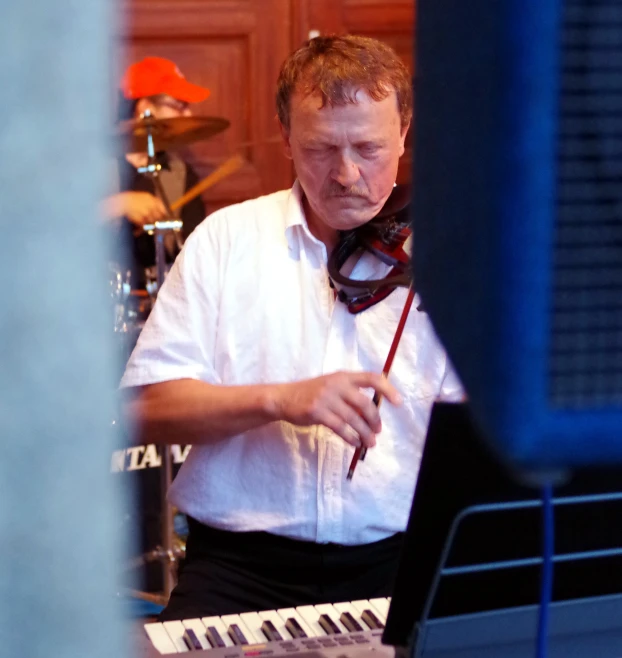 a man in white shirt playing an organ keyboard