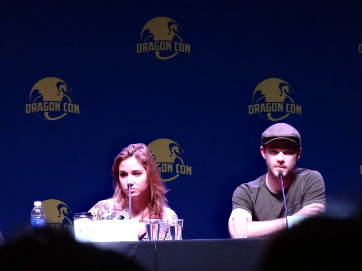 the man and woman are sitting on a stage with microphones