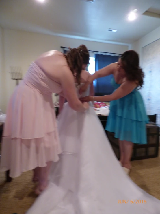 the two women are getting ready to tie the strap of the dress