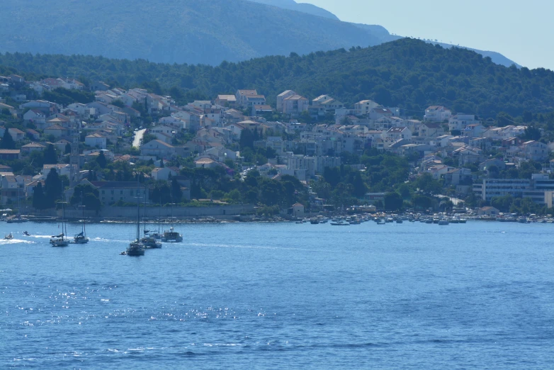 three boats are out on the water by a hillside