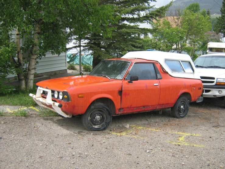 an orange car sits parked next to another white truck