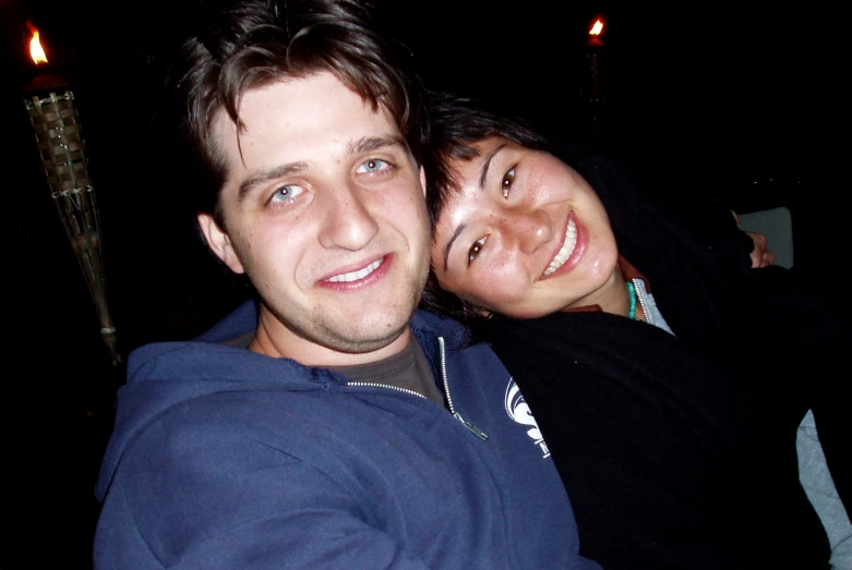 two people posing for the camera with candles in the background