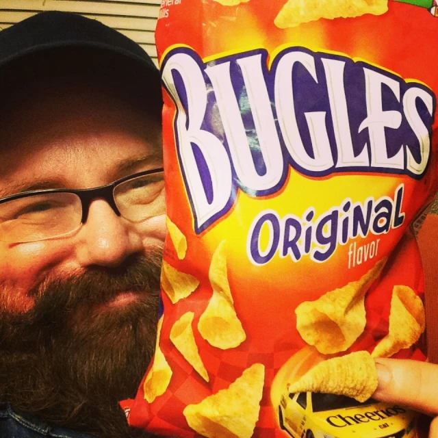 a man in glasses holding a bag of slugies chips