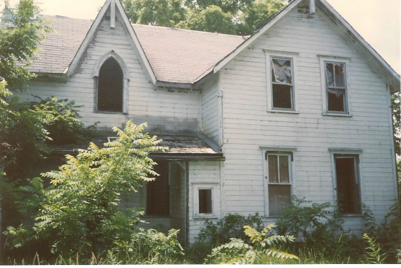 an old dilapidated white house sitting among a forest