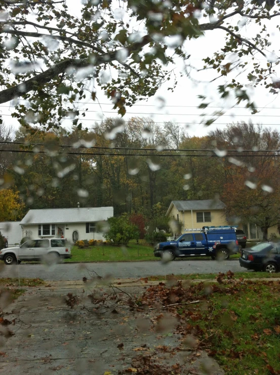 a rainy view through the window at some cars parked in the driveway