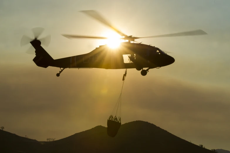 a helicopter and a construction crane are being hoisted from a hill