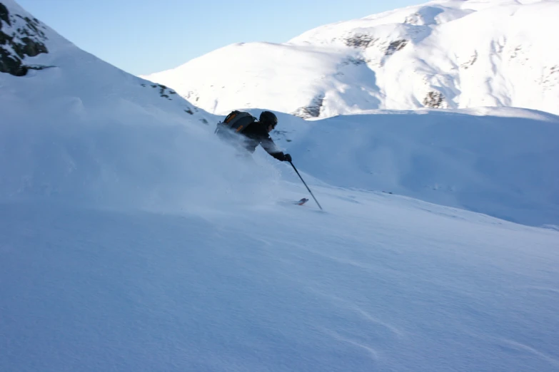 a skier moves along the mountain on a bright day