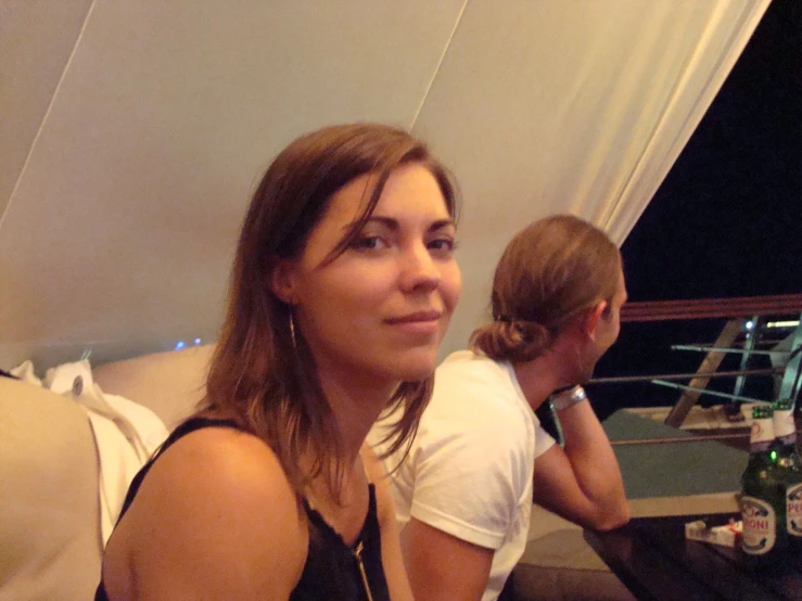 a woman looks over her shoulder on a couch with a beer bottle and a chair nearby