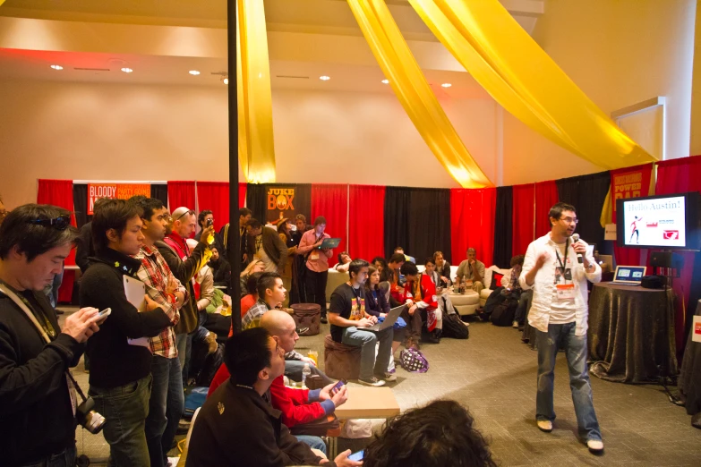 a crowd is standing around while a man is talking