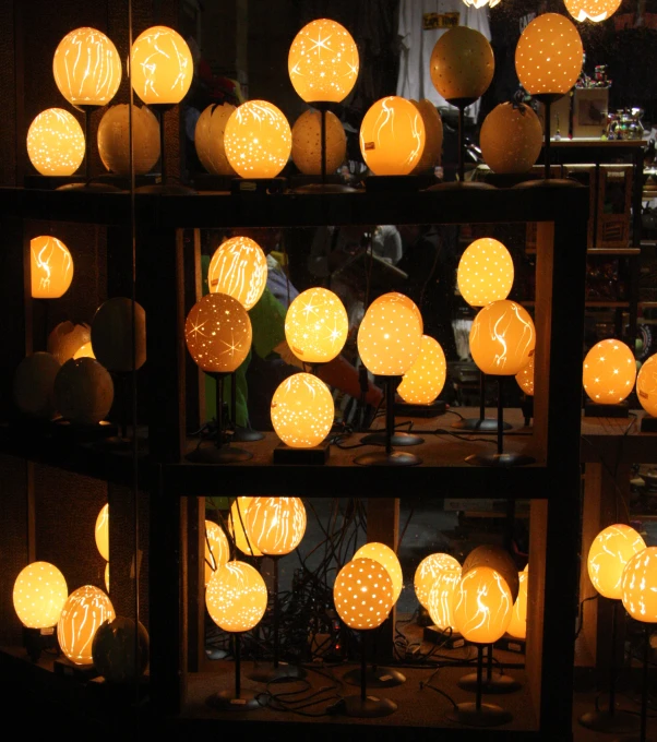 lighted paper lanterns sit next to each other on shelves