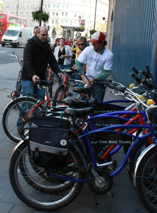 a group of people standing near a line of parked bikes