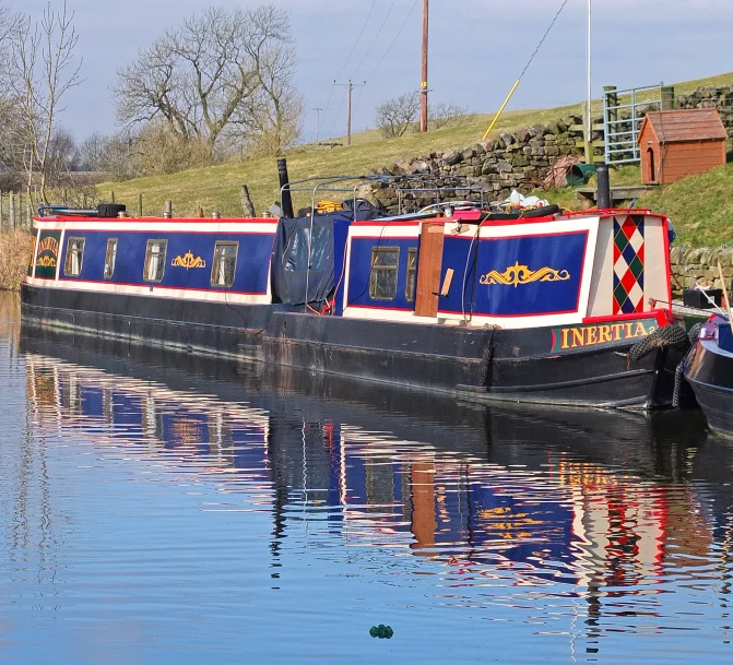 a red and blue barge on water next to hills