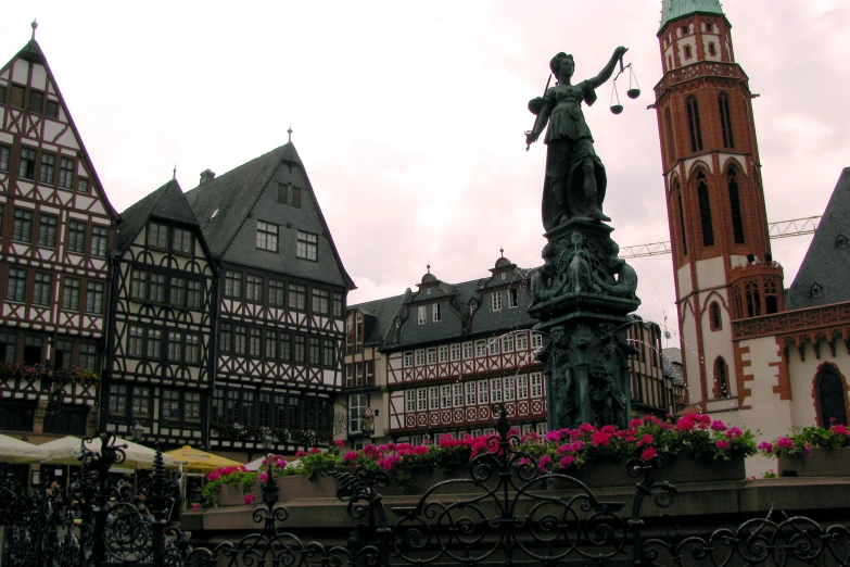 statue with flowers on the ledge in front of buildings