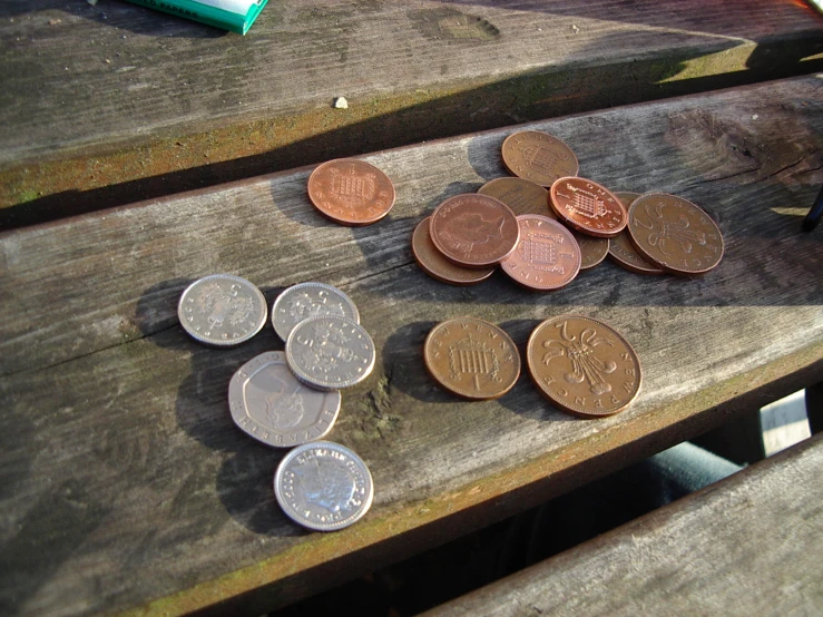 a number of coins scattered on the ground near a can of soda