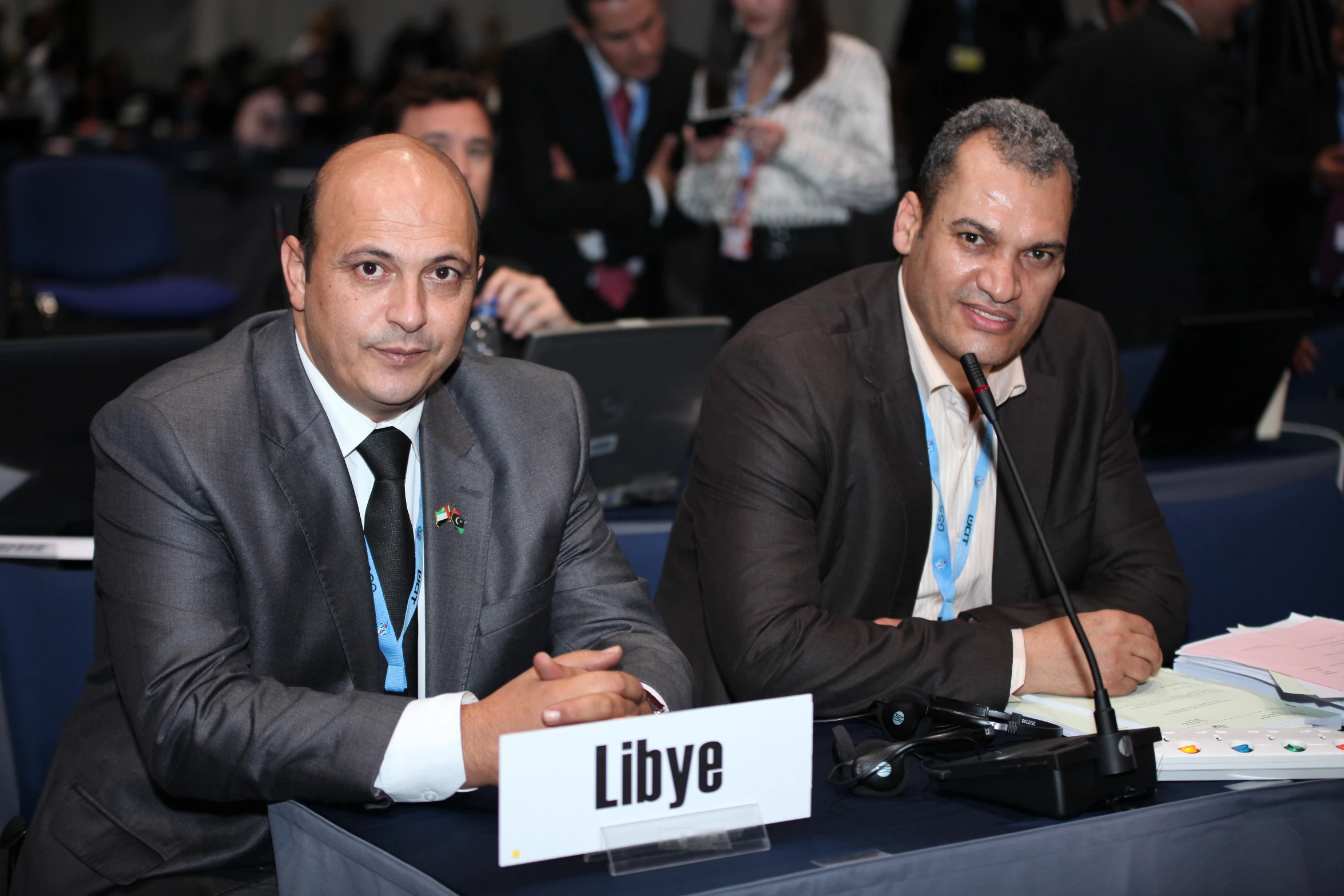 two men sitting at tables at a meeting