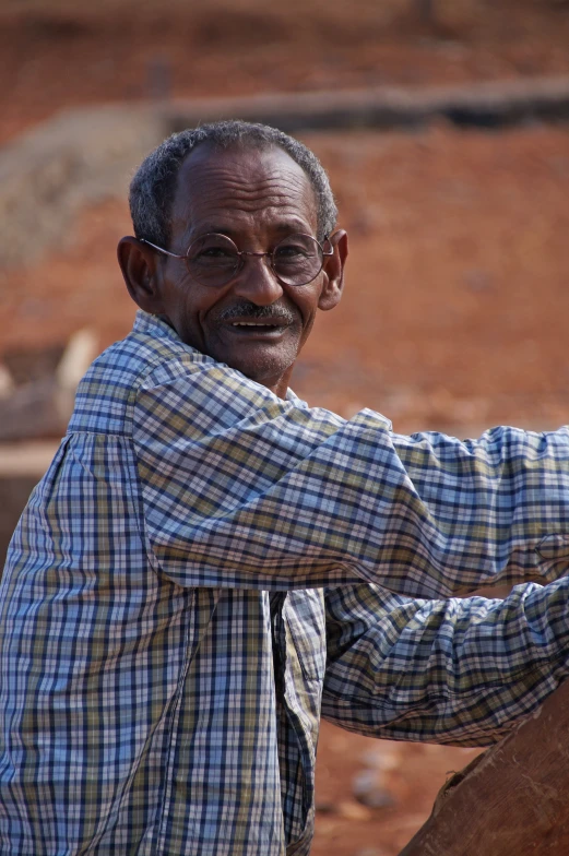 a man with glasses wearing a blue and black checked shirt