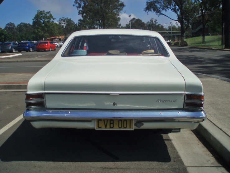 the rear end of a vintage white car parked on the side of the road