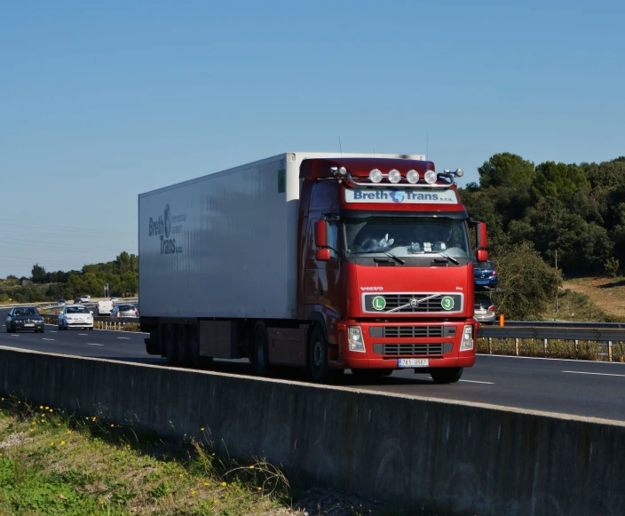 a red semi truck with a big trailer drives down a highway