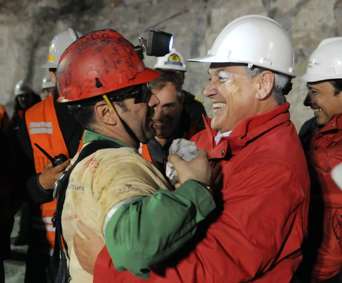 a group of men in hard hats and safety gear standing around each other