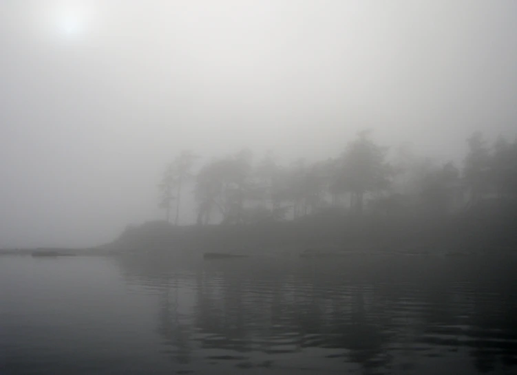 an island sits in the middle of a foggy lake