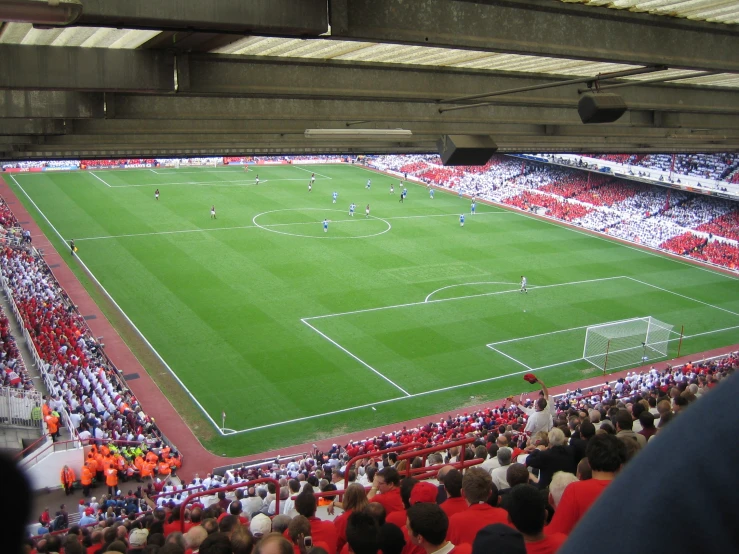 a soccer field with people standing in the stands watching it