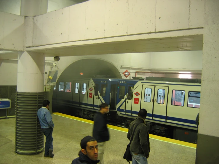 a group of people standing near to an empty subway car