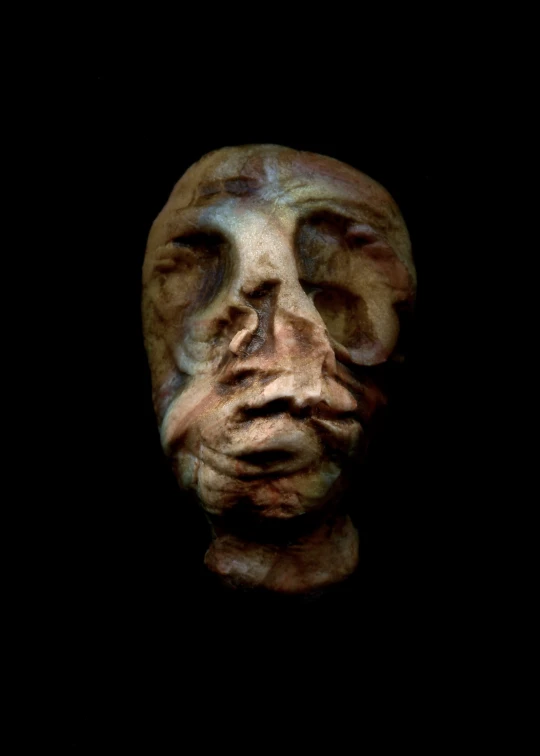 an old, worn and stained carved face on a black background