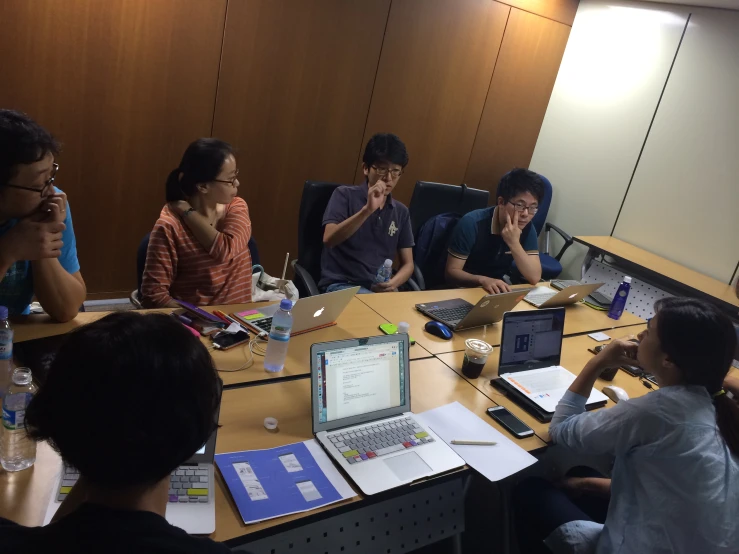 a group of people sitting at a table around computer screens