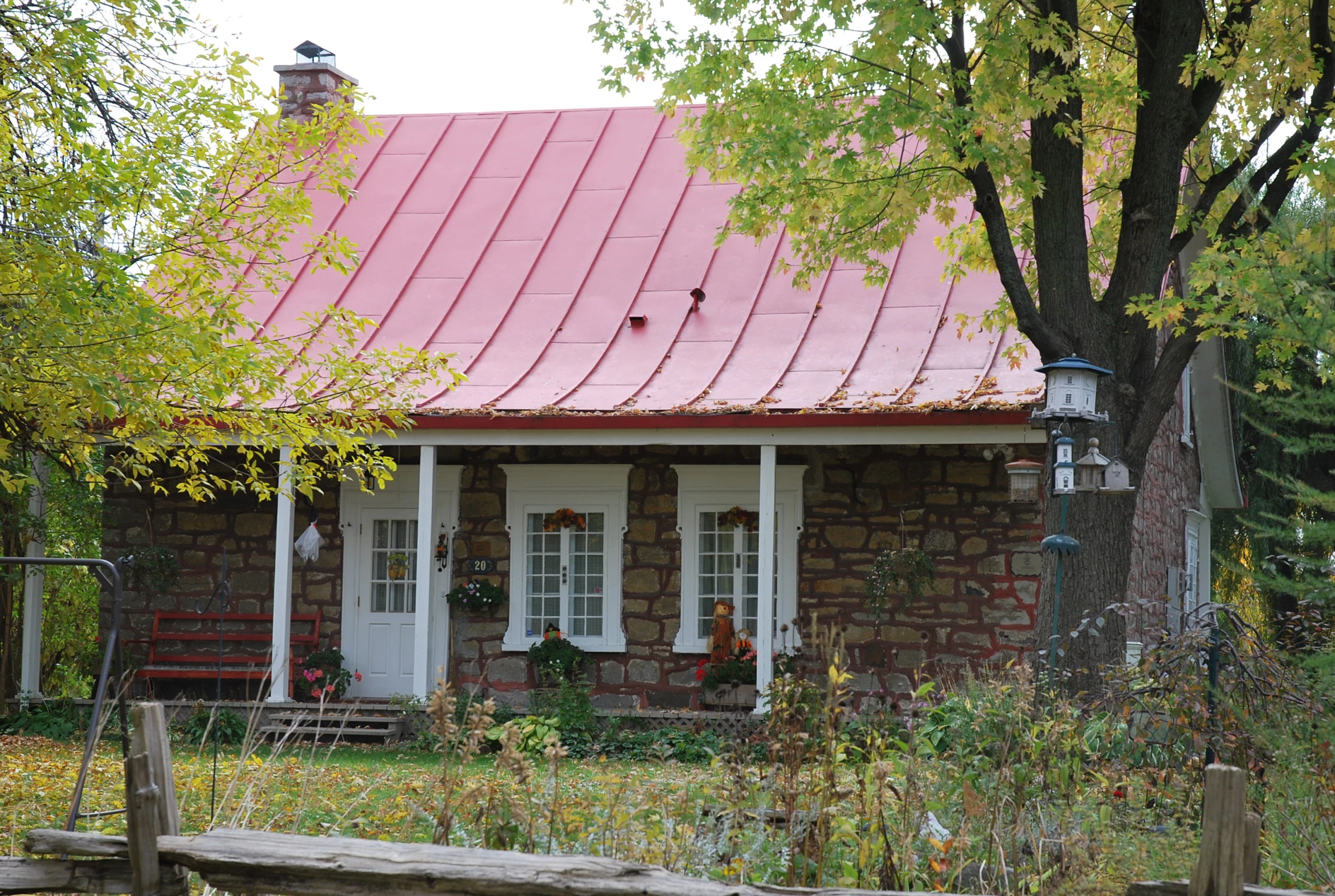 a small brick house with a red roof sits among trees