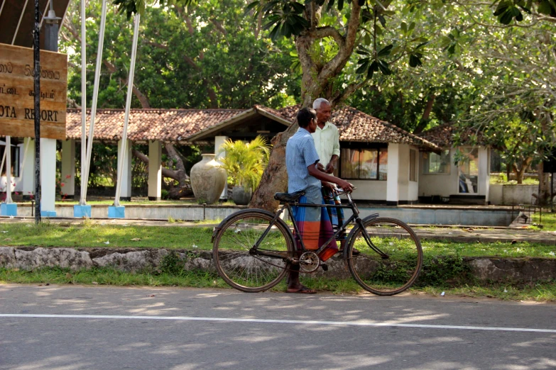 a man standing next to his bicycle near some grass