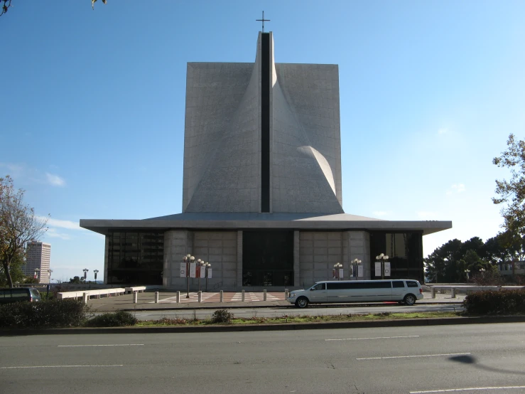 a large church sitting across from another building with an old white van in front