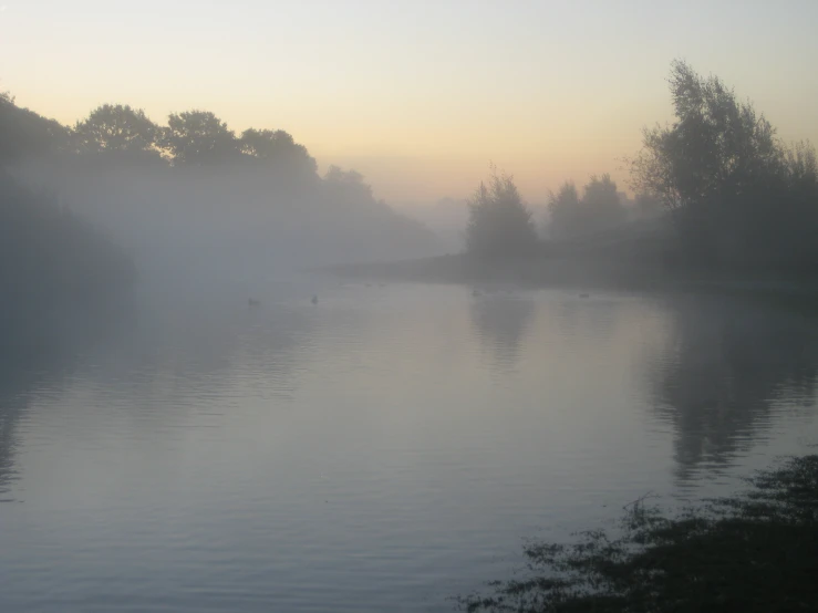 fog hangs over the river and boats on the water