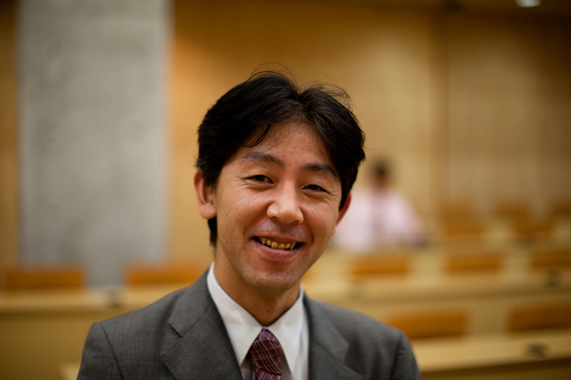 a man in a suit smiles in front of rows of seats