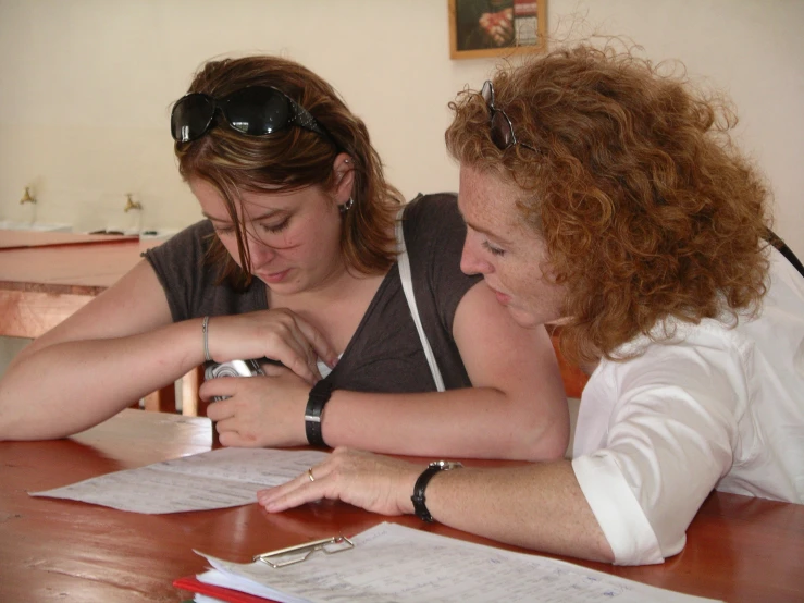 two women sitting at a table working on soing