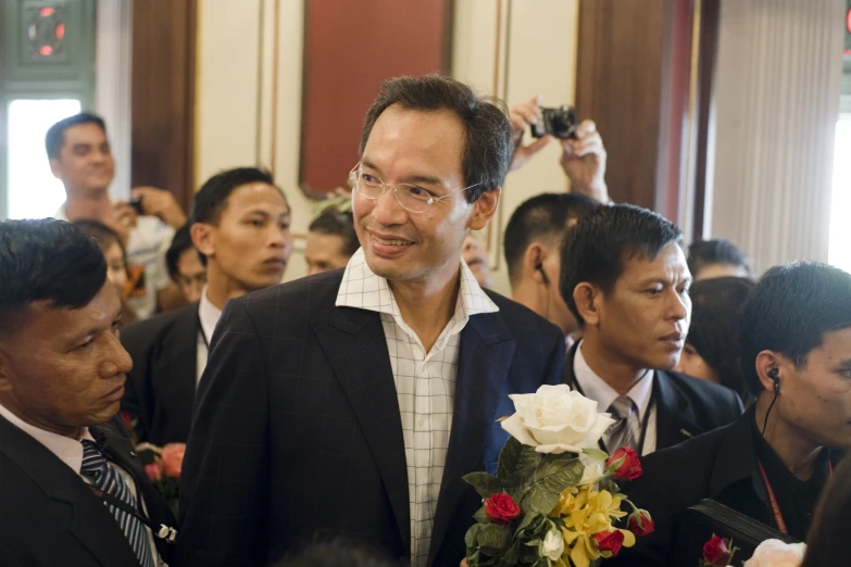 an asian man standing in a room full of people